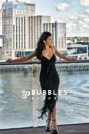 Arianna in front of a river in a classy tight black dress