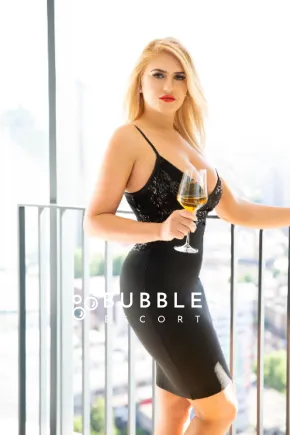 Anastaia wearing a tight black dress holding a glass of wine