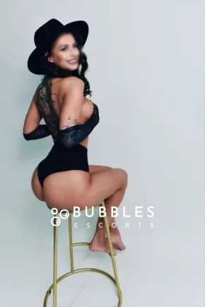 Amy sitting on a barstool while showing off her ass in a black leotard 