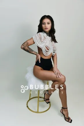 Amy sitting on a barstool while rocking a pearly top 